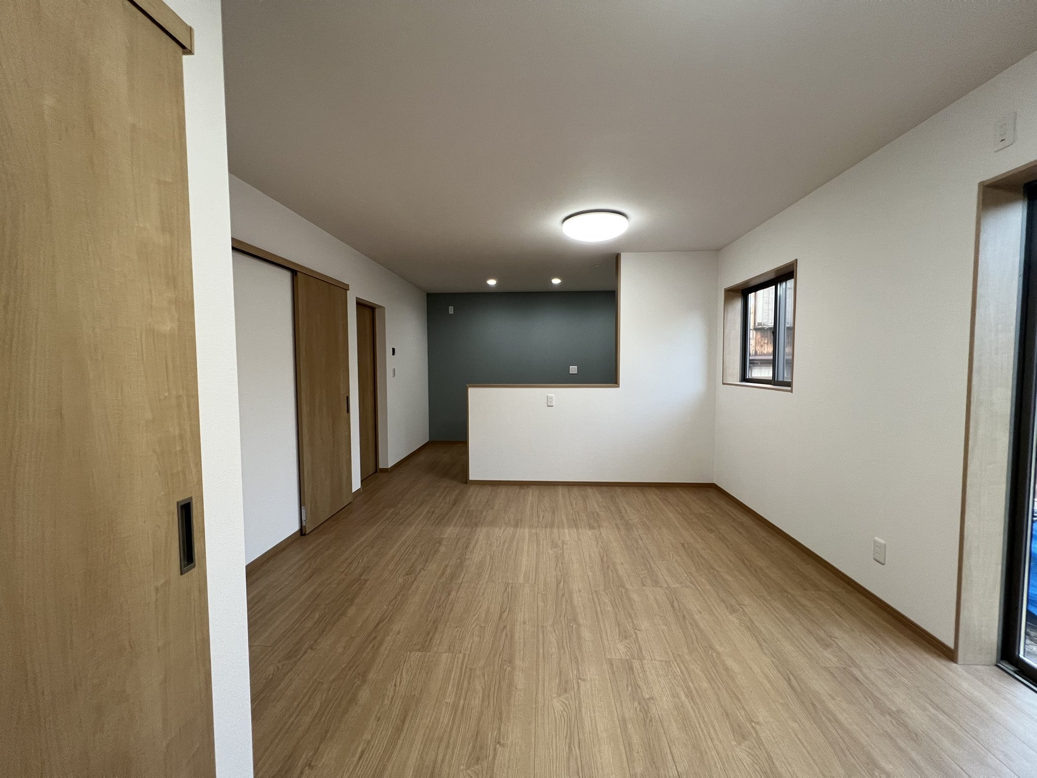 フローリングと白い壁のLDKに生まれ変わった同じ部屋
